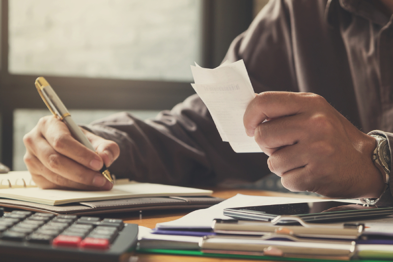 A Person Holding a Brass Pen Holding a Piece of Paper